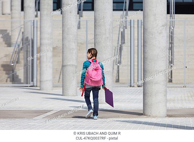 Girl carrying folder in courtyard