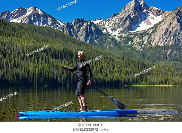 Caucasian man on paddleboard on mountain lake