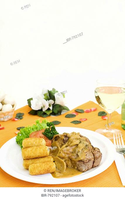 Pork filet and sauteed mushrooms in cream sauce served with croquettes and a glass of white wine