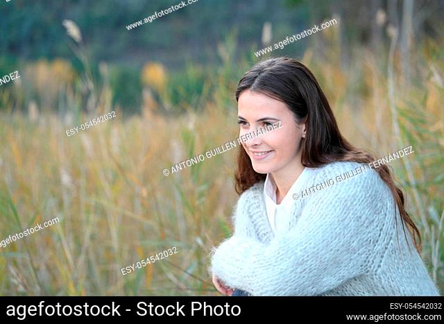 Happy teenage girl wearing a sweater looking away on a field in winter