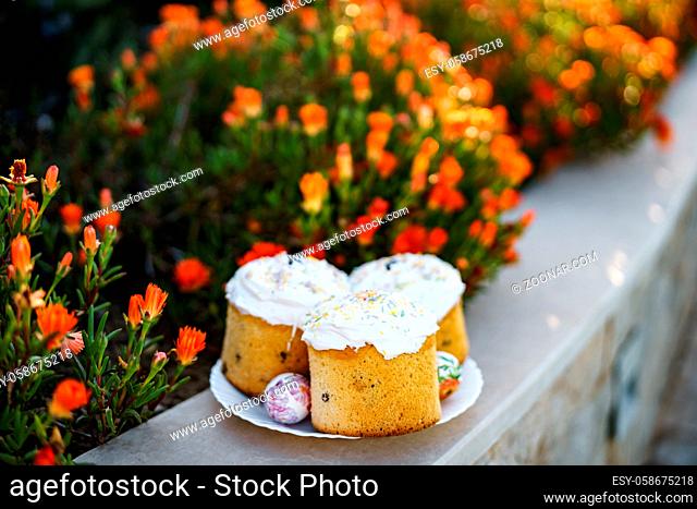 Easter eggs and pies with cream topping on flower and nature background