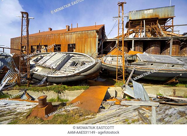 Old boats in abandoned whaling station full of broken machinery, collapsing buildings, barrels, pipes and tanks, Leigh Harbour