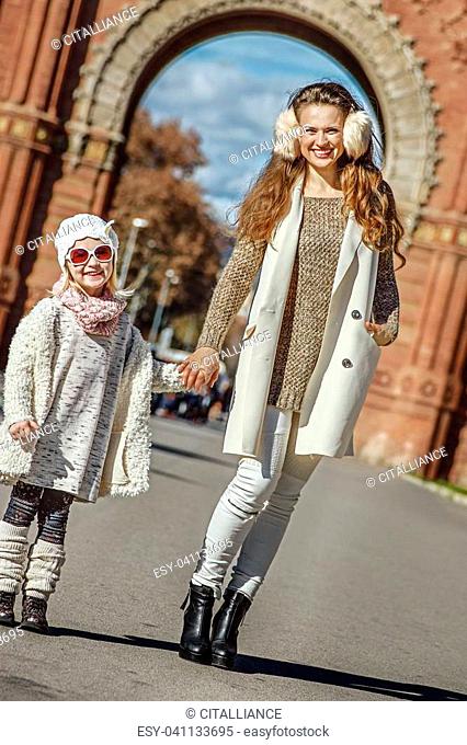 in Barcelona for a perfect winter. Full length portrait of happy trendy mother and child standing near Arc de Triomf in Barcelona, Spain