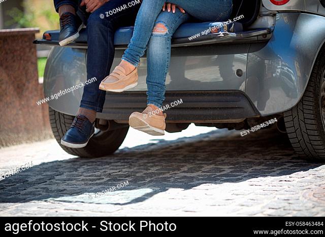 Closeup picture of tourist man's and woman's legs while sitting in car. People enjoying traveling or having journey, trip, voyage etc