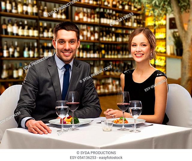 smiling couple with food and wine at restaurant