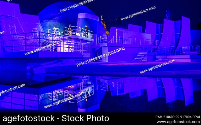 07 June 2021, Mecklenburg-Western Pomerania, Schwerin: Singers and actors are reflected in a body of water in the musical ""Titanic"" on the stage of the...