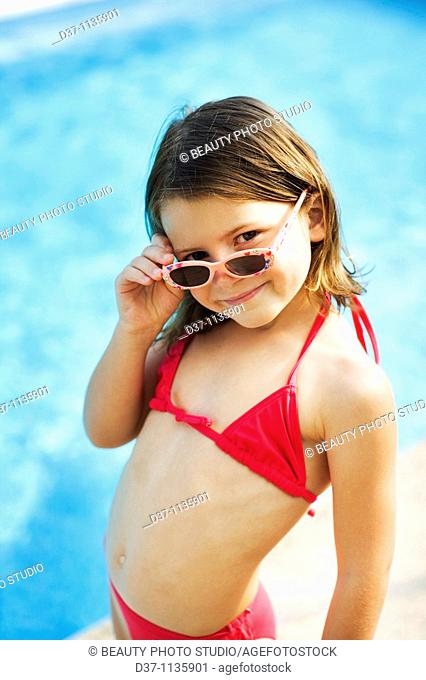 Young girl in bikini, looking over sunglasses