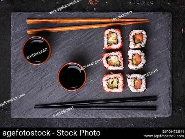 Top view of traditional japanese cuisine. Sushi rolls with salmon and tuna fish on black sushi board from above