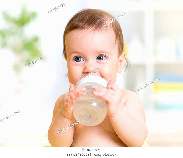 sweet baby girl holding bottle and drinking water