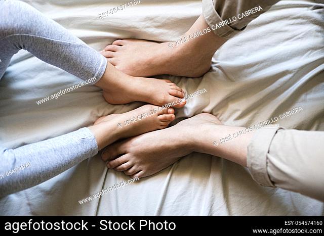 Mother and child cross their feet together as they sit on some beige bed sheets. It's a tender moment as they compare how similar they are