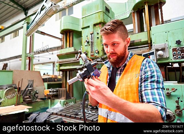 Arbeiter in der Werkstatt der Metallfabrik prüft konzentriert ein Zentriergerät mit Messuhr