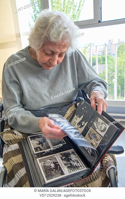 Old woman leafing through a family photo album in a nursing home
