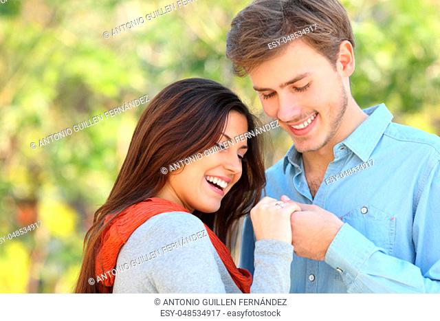 Happy couple looking at engagement ring after proposal in a park
