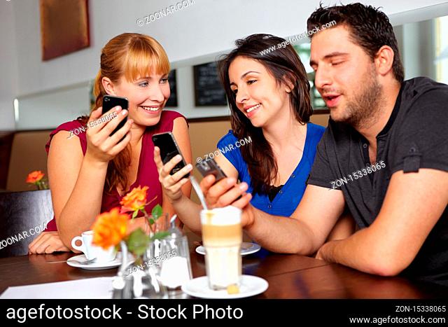 Freunde im Café surfen im Internet mit ihren Handys