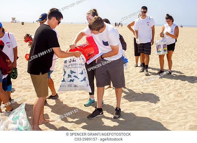Young adult volunteers fill trash bags at a weekend cleanup in Huntington Beach, CA