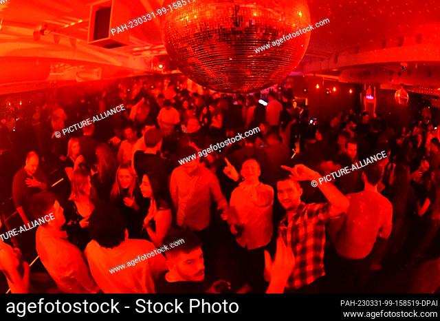 PRODUCTION - 27 January 2023, Bavaria, Munich: Guests dance in the 089 Bar in Munich with red lighting and strong beats until deep into the night