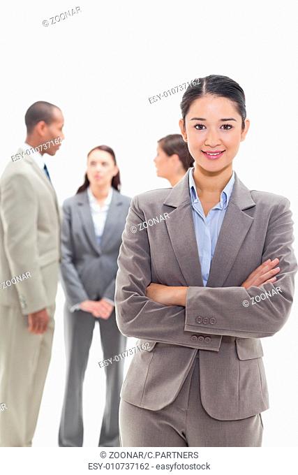 Businesswoman smiling and crossing her arms with co-workers