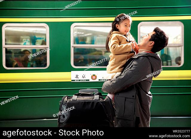 Father holding his daughter standing on the platform at the railway station