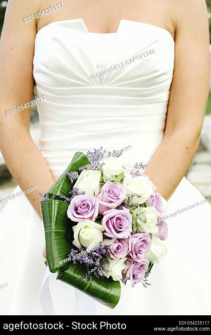 Hands of the bride with a bouquet of flowers