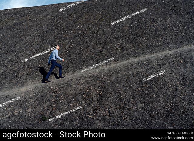 Mature businessman walking up a disused mine tip