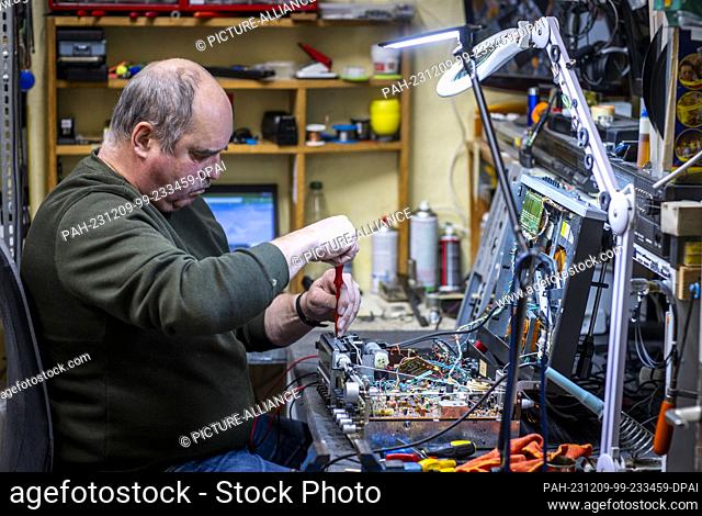 PRODUCTION - 28 November 2023, Mecklenburg-Western Pomerania, Schwerin: Jens-Uwe Peters repairs old radios, record players and hi-fi systems in his small...