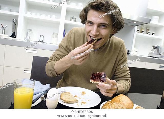 Portrait of a young man eating a slice of bread