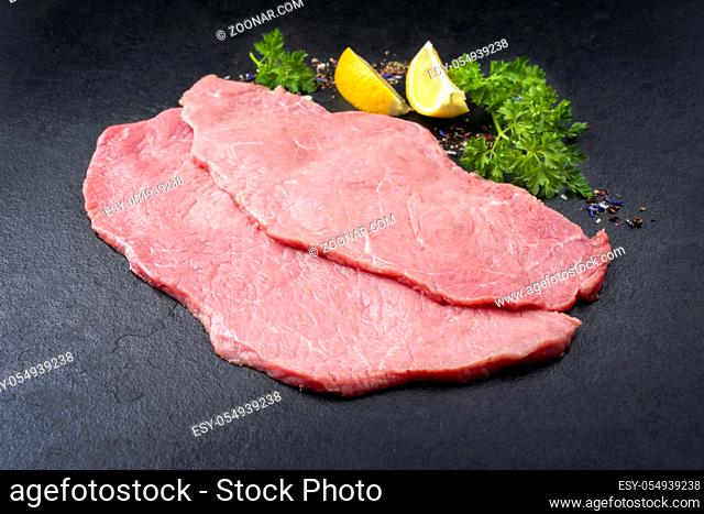 Raw veal schnitzel from topside as closeup on black background with copy space