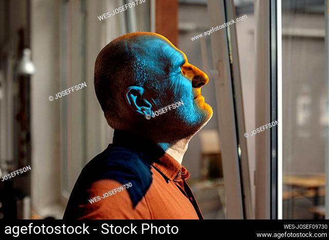 Businessman with blue light on face at office