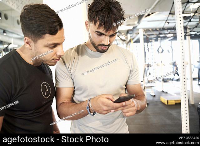 Two men looking at smart phone in gym