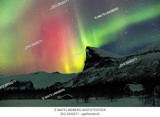 Northern light, Aurora borealis, over Sarek national park taken from Aktse, with an old barn and house, Mount Skerfe and Namatj, slightly movement in the stars