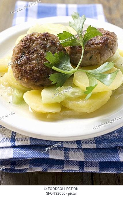 Burgers on potato and cucumber salad with parsley