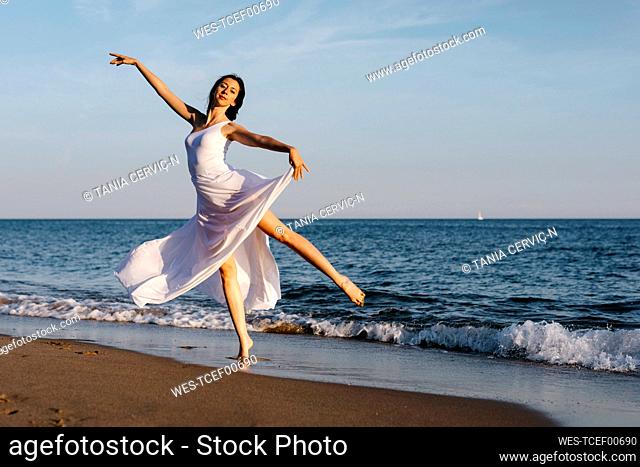 Ballerina in white dress dancing at the sea