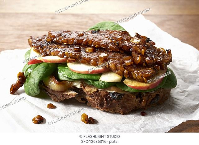 Marinated Lupini Bean Tempeh open-faced sandwich with sliced apple, spinach and grilled onions