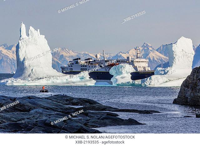 The Lindblad Expeditions ship National Geographic Explorer at anchor behind iceberg near Qilakitsoq, western Greenland