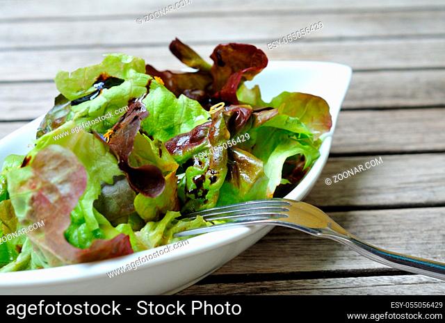 Fresh salad on a wooden table. Frischer lollo rosso Salat