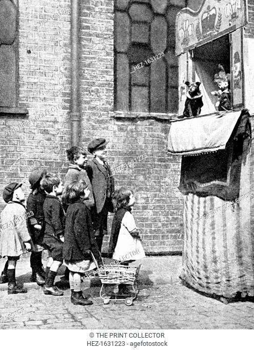 Children watching a Punch and Judy show in a London street, 1936. From Peoples of the World in Pictures, edited by Harold Wheeler