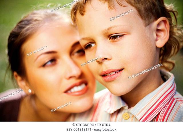 Close-up of a boyâ€™s face and his mother looking at him in the background