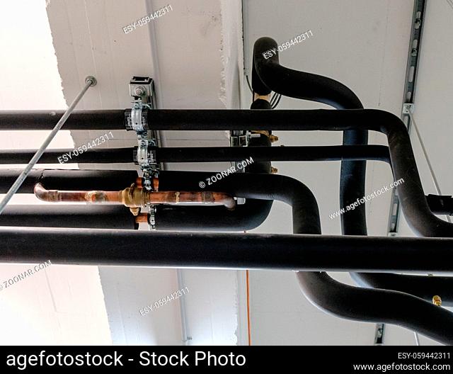 metal and plastic pipe system on the cellar ceiling of an apartment building with water and heating pipes
