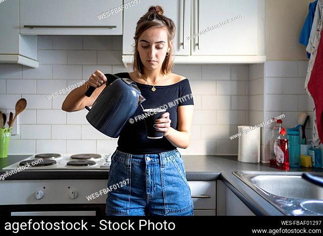 Young woman preparing an instant coffee in kitchen at home