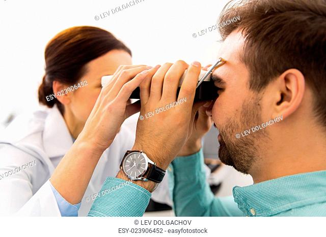 health care, medicine, people, eyesight and technology concept - close up of optometrist with pupillometer checking patient intraocular pressure at eye clinic...