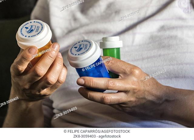 Woman examining medication treatment, several bottles in the hand, conceptual image