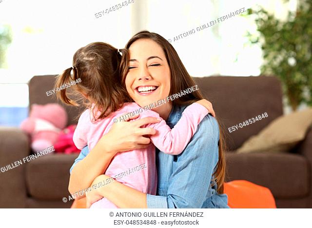 Happy mother embracing to her baby daughter in the living room at home