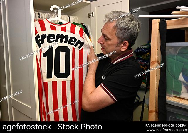 PRODUCTION - 08 August 2022, Bremen: Arnd Zeigler shows a jersey from his collection in his studio . The stadium announcer for Werder Bremen and host of the...