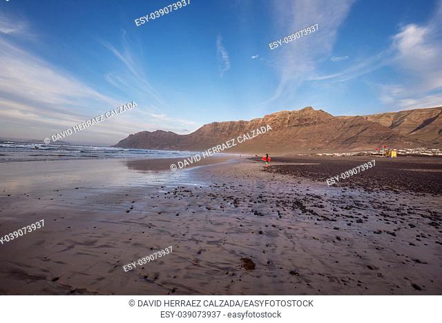 Unidentifiable surfers in famous Famara beach in Lanzarote, Canary islands, Spain