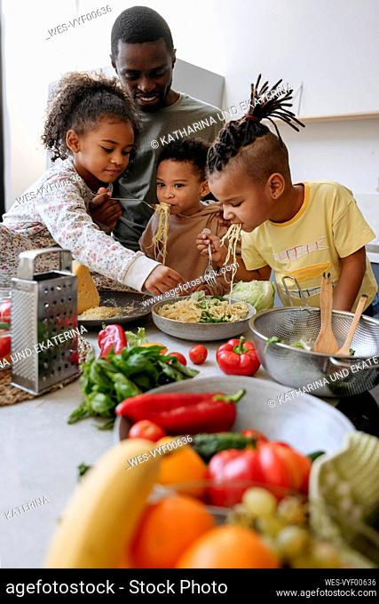 Family enjoying spaghetti in kitchen at home