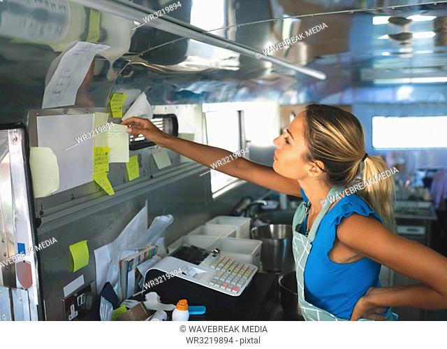 Woman waitress looking at orders on sticky notes