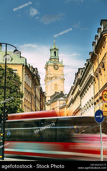 Stockholm, Sweden. Red Bus In Motion Blur Rides Near Old Town With Tower Of Storkyrkan - The Great Church Or Church Of St. Nicholas