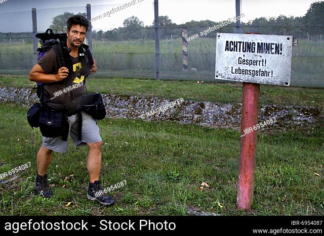Hiker, man with backpack at sign Achtung Minen, border fence, expanded metal fence, border signal fence, barbed wire fence, Wrechower Aue