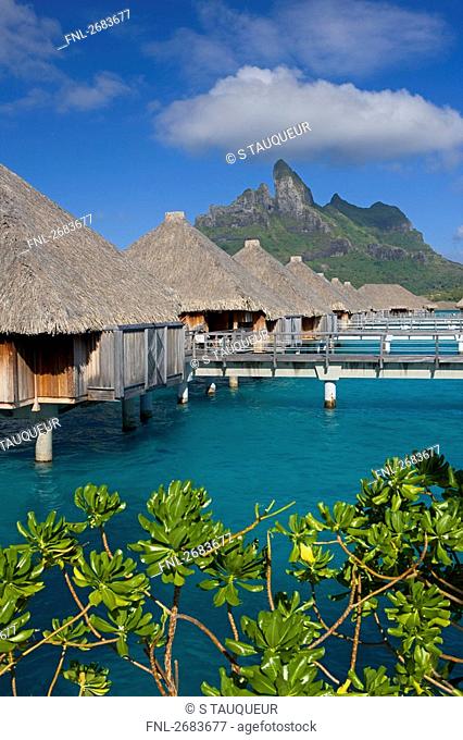 Thatched roof huts in shallow water, Saint-Regis Resort, Bora Bora, Society Island, French Polynesia