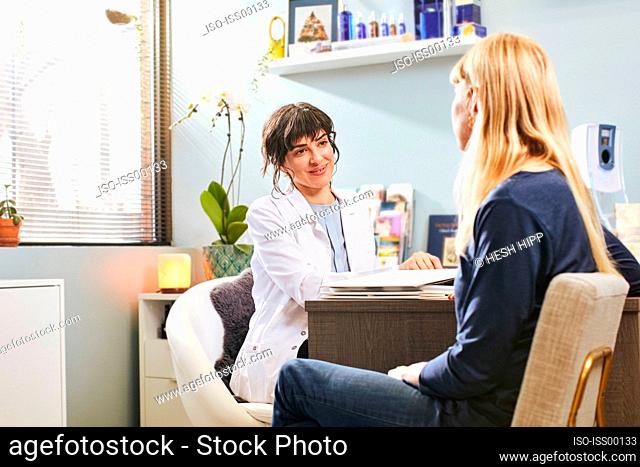 Beautician talking to patient at desk